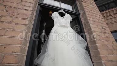 <strong>白色</strong>婚纱挂在阳台的<strong>光圈</strong>窗口和砖块场景中